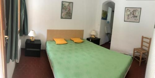 - une chambre avec un lit vert et 2 oreillers jaunes dans l'établissement Villa St MAXIME 150 m de la plage, à La Celle-sous-Gouzon