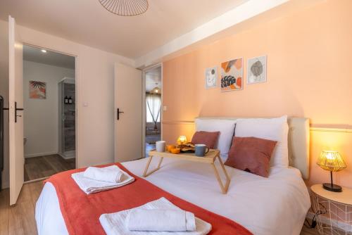 a bedroom with a large bed with a table on it at Le Corallo - T2 cosy et moderne en hyper-centre in Bergerac