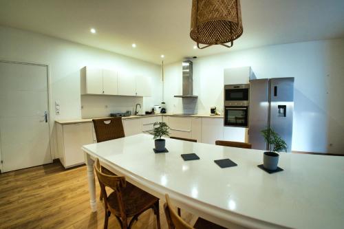 une cuisine avec une grande table blanche et des chaises dans l'établissement Chambre 25m2, SDB PV, 3 pers, Centre, 160m2, WIFI, à Tourcoing