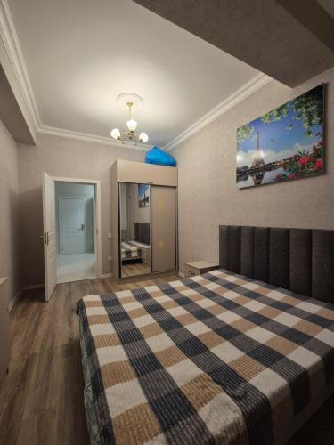 a bedroom with a bed with a checkered blanket at Mirvari City in Sumqayyt