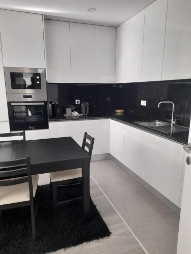 a kitchen with white cabinets and a table and a microwave at Amorosa Apart in Amorosa
