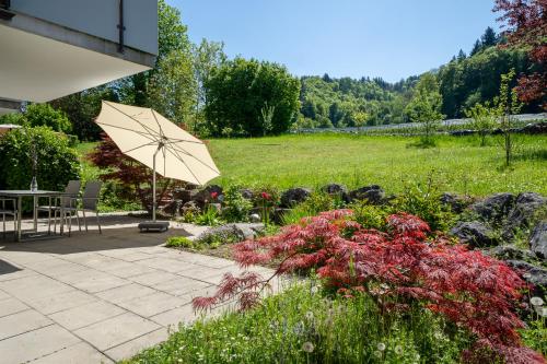 a patio with a table and an umbrella in a garden at Seeliebe und Gartenglück in Bodman-Ludwigshafen