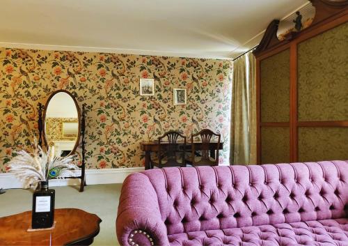 a pink couch in a room with floral wallpaper at The Hall - Historic Grade I-listed Jacobean Mansion in Bradford on Avon