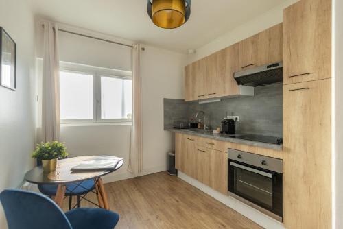 una cocina con armarios de madera, una mesa y un tocador en Le Néo - Studio chic avec sa cour privative et fibre, en Bergerac