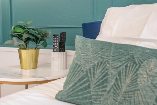 a bed with a table with a pillow and a plant at Le Néo - Studio chic avec sa cour privative et fibre in Bergerac