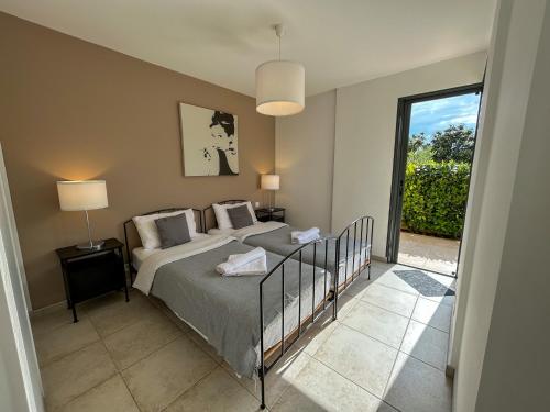 une chambre avec un lit et une grande fenêtre dans l'établissement La Bergerie - Modern villa with pool in private domain, à Saint-Paul-de-Vence