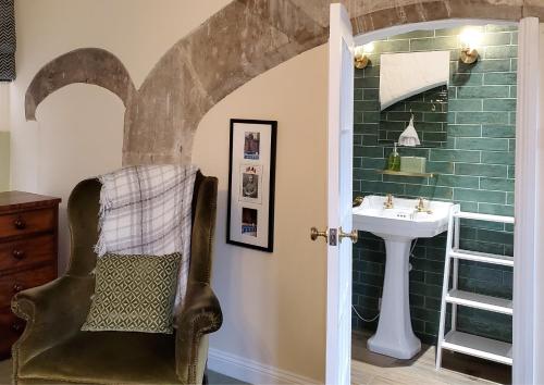 a bathroom with a sink and a chair at The Hall - Historic Grade I-listed Jacobean Mansion in Bradford on Avon