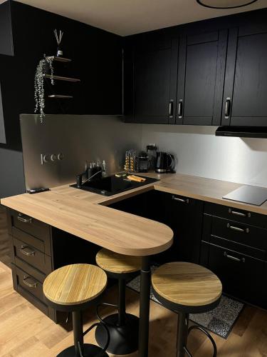 une cuisine avec des armoires noires et un îlot en bois avec des tabourets dans l'établissement Studio a Berck proche plage, à Berck-sur-Mer