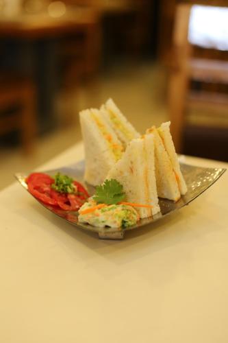 a plate of sandwiches and tomatoes on a table at ROYAL ROSETTE LAKE VIEW Bhimtal in Nainital