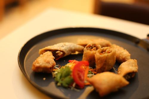 a black plate of food with broccoli and vegetables at ROYAL ROSETTE LAKE VIEW Bhimtal in Nainital
