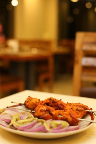 a plate of food with chicken and onions on a table at ROYAL ROSETTE LAKE VIEW Bhimtal in Nainital