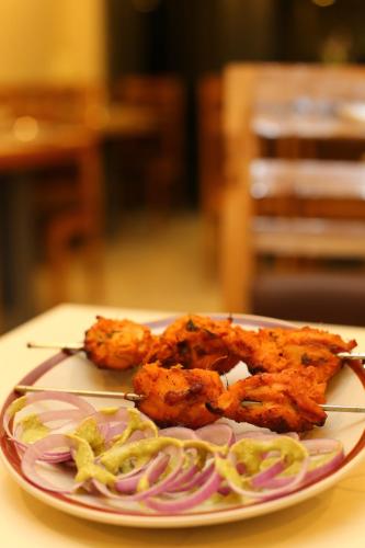 a plate of food with chicken wings and onions at ROYAL ROSETTE LAKE VIEW Bhimtal in Nainital