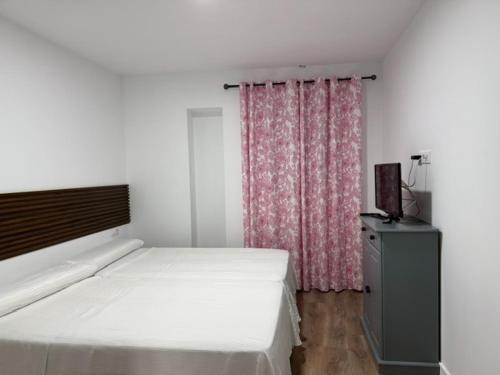 サンルーカル・デ・バラメダにあるApartamento Castilloのベッドルーム1室(ベッド1台付)、窓(カーテン付)