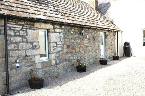 a stone building with potted plants in front of it at Borlum House in Thurso