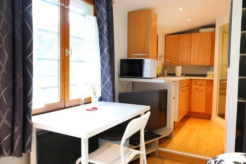 une petite cuisine avec une table blanche et un four micro-ondes dans l'établissement J home, à Villeneuve-le-Roi