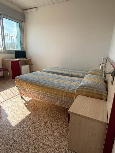 a bedroom with a bed and a desk and a window at Rooms Casa Celeste sul Mare in Cesenatico