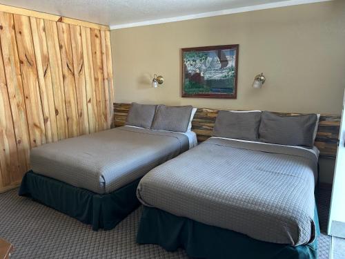 two beds in a room with wooden walls at Birch Glen Hotel in Cascade