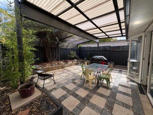 a patio with a table and chairs under a pergola at Rest on Keppel in Bathurst