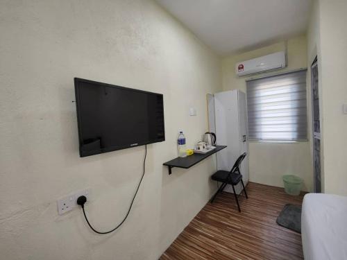 a living room with a flat screen tv on a wall at Reds Roomstay Pantai Penarik 1 in Pulau Che Selamah