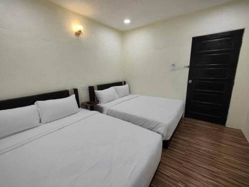 two beds in a small room with white sheets at Reds Roomstay Pantai Penarik 1 in Pulau Che Selamah