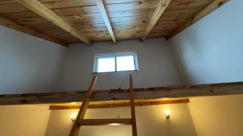 a room with a wooden ceiling and a window at Pine Edge by T2R - Luxury Duplex Apartment Private Parking & Stunning Views in Khaira Gali near to Nathia Gali & Muree in Khaira Gali