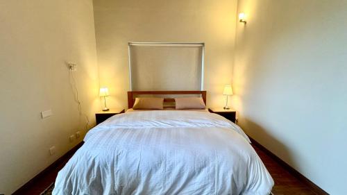 a bedroom with a bed with two lamps on both sides at Pine Edge by T2R - Luxury Duplex Apartment Private Parking & Stunning Views in Khaira Gali near to Nathia Gali & Muree in Khaira Gali