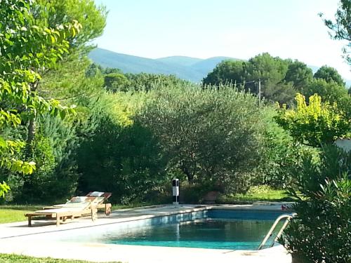 - une piscine avec 2 chaises et un banc à côté dans l'établissement Maison de charme en Luberon à proximité de Lourmarin piscine privée et grand jardin, à Puyvert