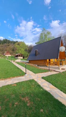 a large wooden building with a black roof at Vikendica i odmaraliste JuliE, Sarajevo-Jahorina in Tvrdimići