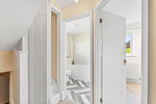 a white bathroom with a tub and a toilet at Cambridge 2 Bed House near City Centre & Science Park in Milton