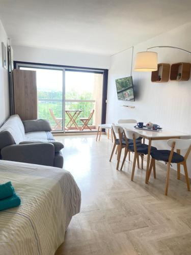 un salon avec un lit, une table et des chaises dans l'établissement Grand studio calme avec piscine - Mandelieu, à Mandelieu-la-Napoule