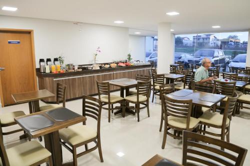 a man sitting at a table in a restaurant at Rota Hoteis Itumbiara in Itumbiara