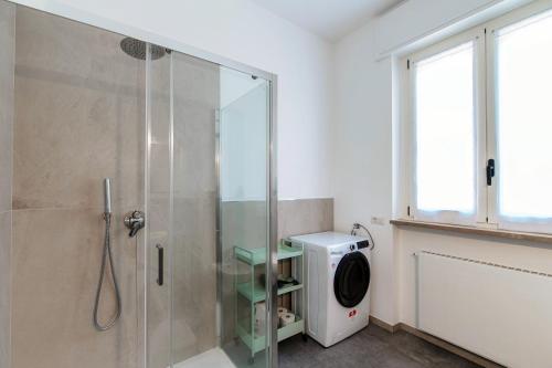 a bathroom with a shower and a washing machine at Villa del Sole - Lake Como Garden in Cernobbio
