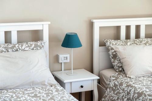 a bedroom with two beds and a lamp on a night stand at Villa del Sole - Lake Como Garden in Cernobbio