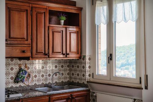 a kitchen with wooden cabinets and a sink and a window at Villa del Sole - Lake Como Garden in Cernobbio