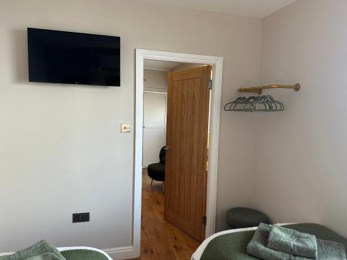 a bedroom with a bed and a door with a television at The Hideaway At The Busfeild Arms in Bingley
