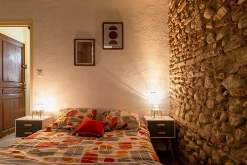 - une chambre avec un lit, 2 tables de chevet et un mur en pierre dans l'établissement Atlas - Nexus, à Perpignan