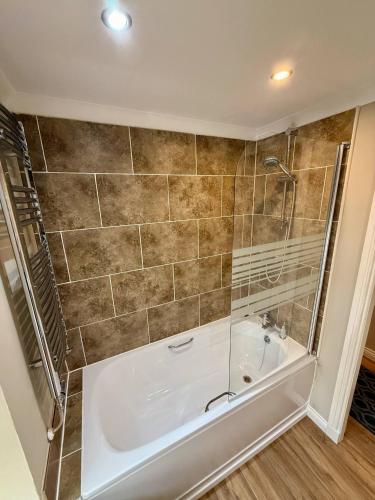 a bath tub in a bathroom with a shower at Airlie Arms Hotel in Kirriemuir