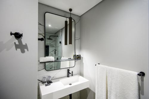 a white bathroom with a sink and a mirror at The Capital Pearls Hotel in Durban