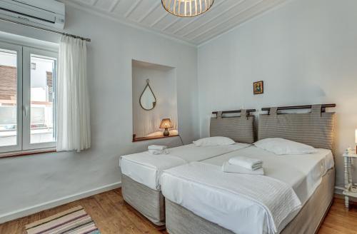 two beds in a white bedroom with a window at Andy Port House with Seaview by Goutos Properties in Ermioni