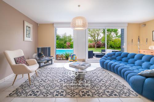 un salon avec un canapé bleu et une table dans l'établissement Maison avec Piscine et Jardin proche Le Mans, à Saint-Pavace