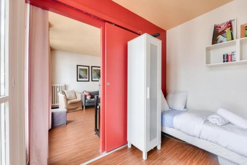une chambre avec un mur d'accent rouge et un lit dedans dans l'établissement Stunning 2BR Flat near Place des Vosges, à Paris