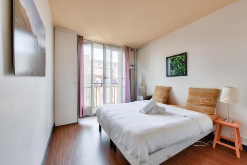 une chambre avec un lit et une grande fenêtre dans l'établissement Stunning 2BR Flat near Place des Vosges, à Paris