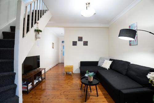 a living room with a black couch and a table at Facilitated 4 BR House & ICC&Darling Harbour-8 mins walk in Sydney