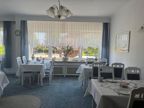 a dining room with white tables and chairs and a window at Rodes Hotel und Restaurant in Rehburg-Loccum