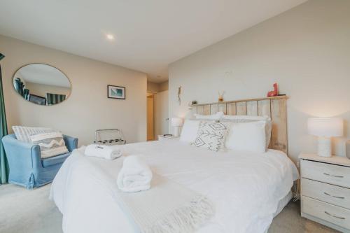 a bedroom with a large white bed and a blue chair at Elevated Ocean View Oasis - 3BR 2 Bath Parking in Christchurch