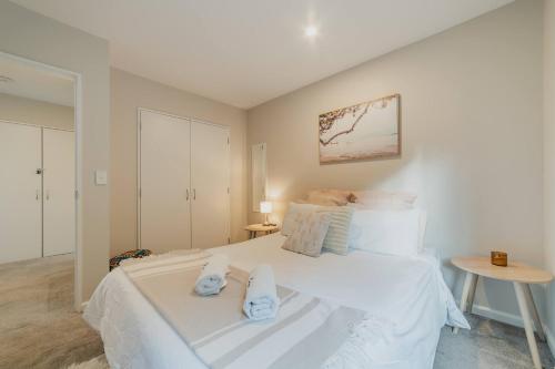 a bedroom with a white bed with towels on it at Elevated Ocean View Oasis - 3BR 2 Bath Parking in Christchurch