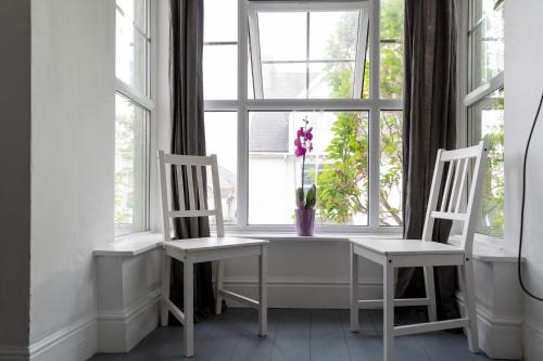 two chairs and a table in a window with a vase of flowers at Palace Guesthouse in Newquay