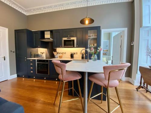 a kitchen with a white table and pink chairs at Beautiful 2 bed apartment in heart of Aberystwyth in Aberystwyth