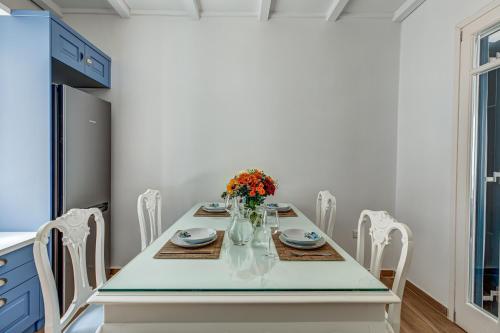 a white dining room with a table and chairs at Andy Port House with Seaview by Goutos Properties in Ermioni