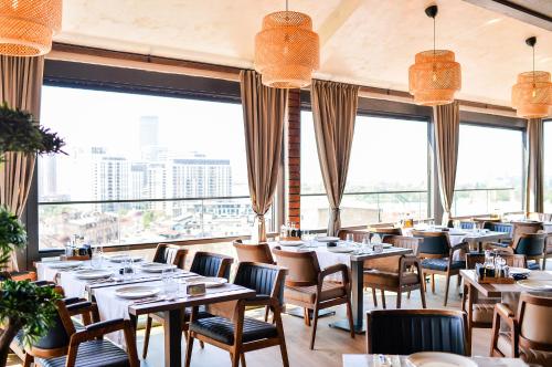 a restaurant with tables and chairs and large windows at Amsterdam Hotel in Belgrade